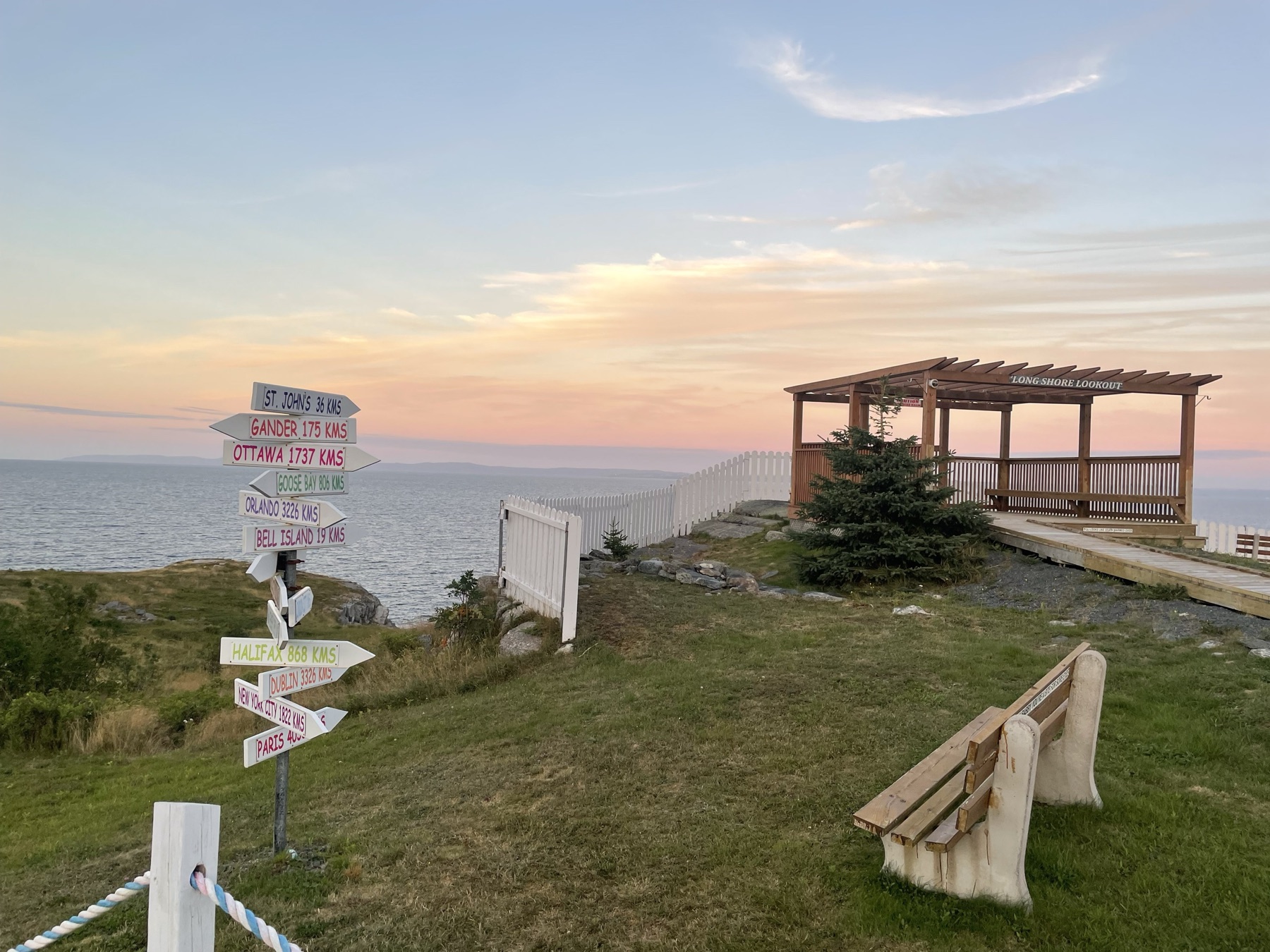 The Long Shore Lookout in Upper Island Cove at sunset, its signpost of distances and the sea beyond